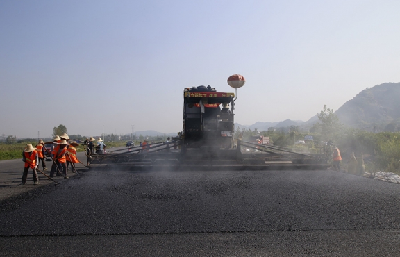 2019年8月，宜春經(jīng)開區(qū)S311路面攤鋪現(xiàn)場，工友們輔助路面兩側(cè)的分料、補窩等作業(yè)